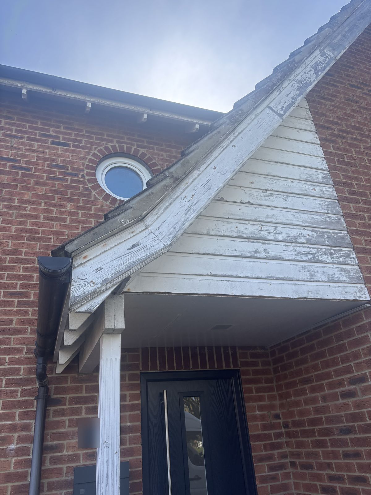 Porch gable before: peeling painted timber fascia and cladding